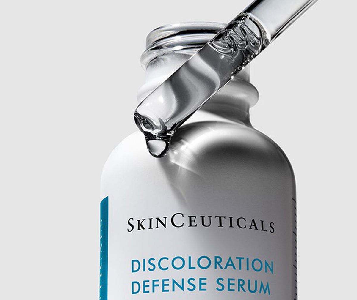 Clear serum dripping from the glass dropper into the Discoloration Defense bottle